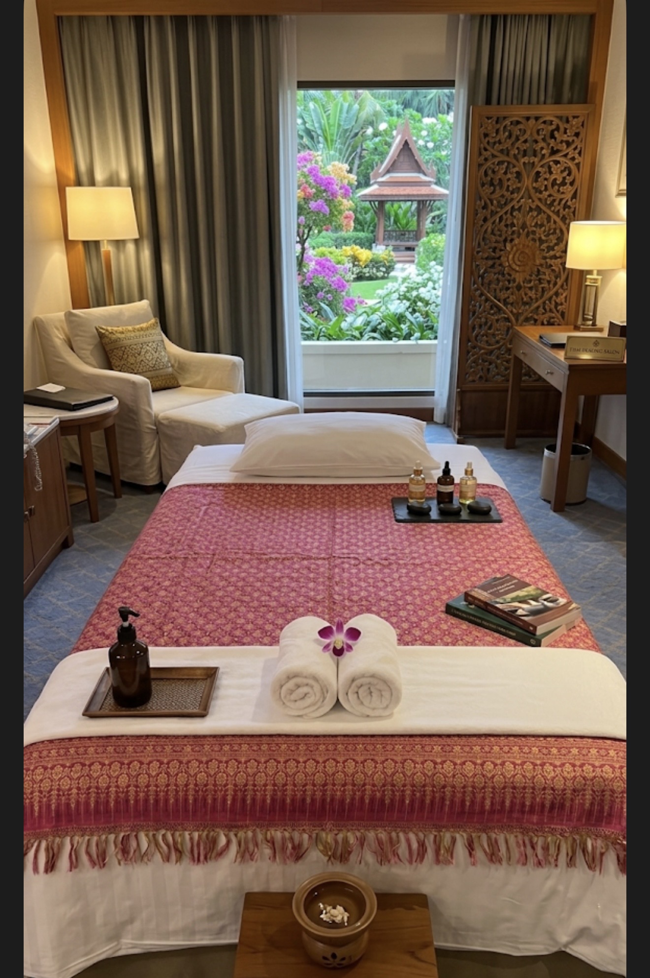 Elegant massage bed prepared in a hotel bedroom with Thai silk, aromatic oils and a tranquil garden view